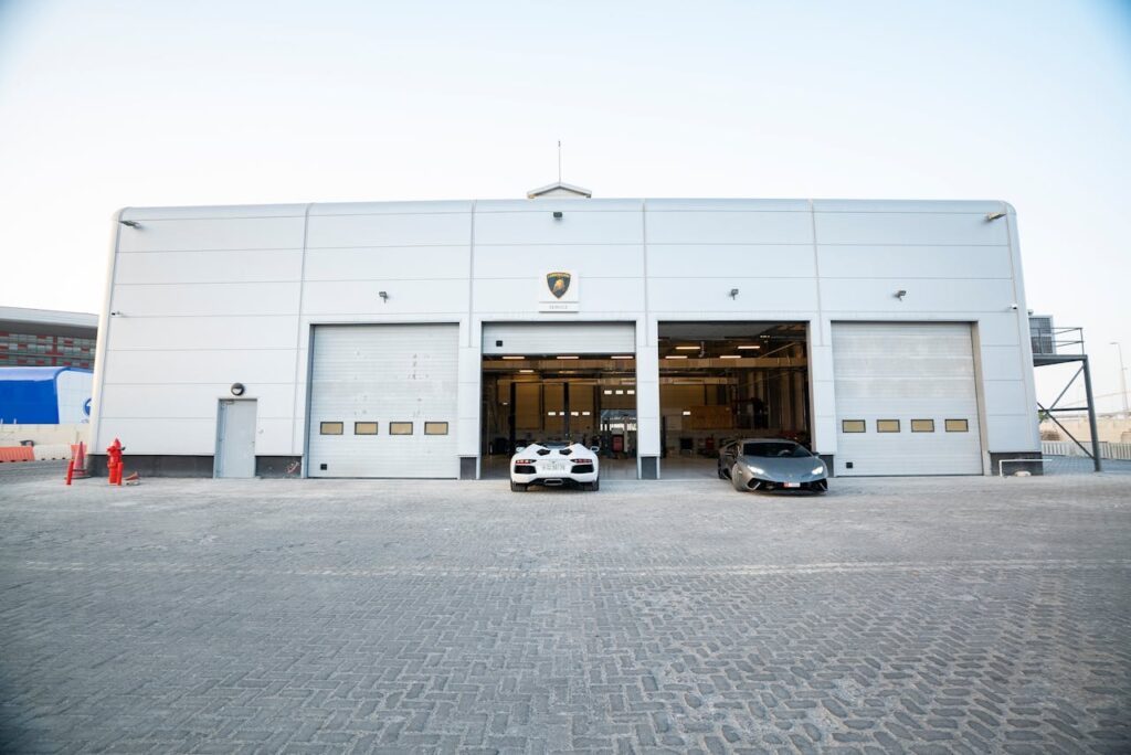 Exterior view of a luxury auto repair shop with sports cars parked in front.