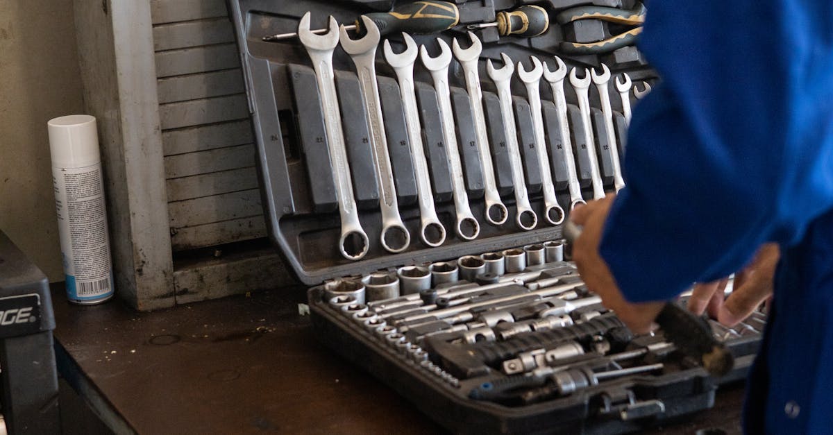Mechanic in blue overalls organizing a toolset in an industrial workshop.